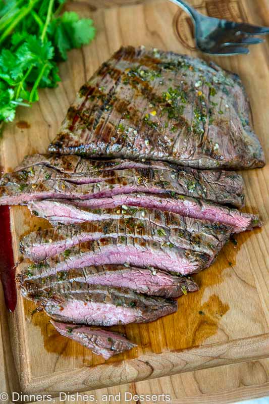 A sliced steak sitting on top of a wooden cutting board, with Steak and Taco