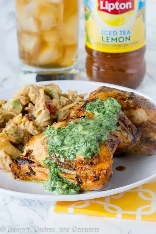 A plate of food with A plate of grilled chicken with herb sauce on top