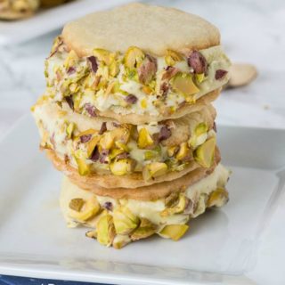 pistachio cookies with pistachio ice cream in the middle stacked on a plate