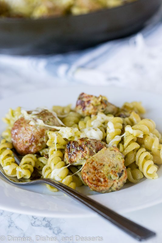 A plate of pesto pasta with meatballs with a fork