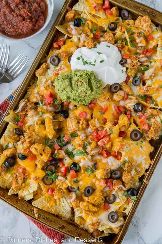 chicken nachos on a tray with guacamole and sour cream