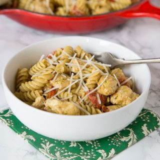 A bowl of food on a plate, with pesto and Pasta