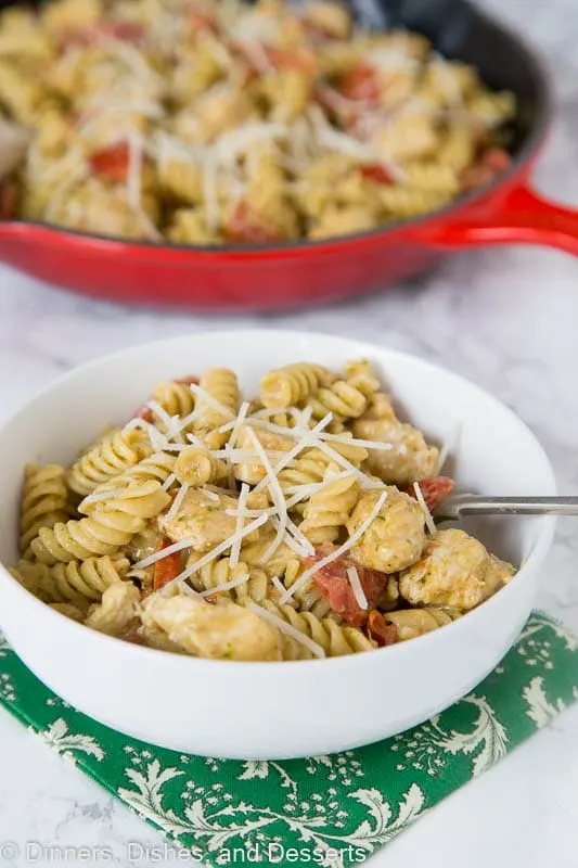 A bowl of food on a plate, with Pesto and chicken pasta