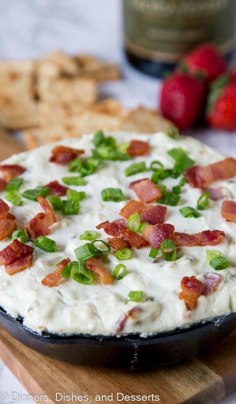 blue cheese dip topped with green onions and bacon in a dish