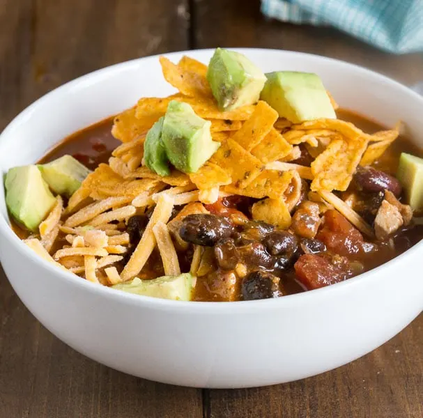 A bowl of food on a plate, with Enchilada and Soup