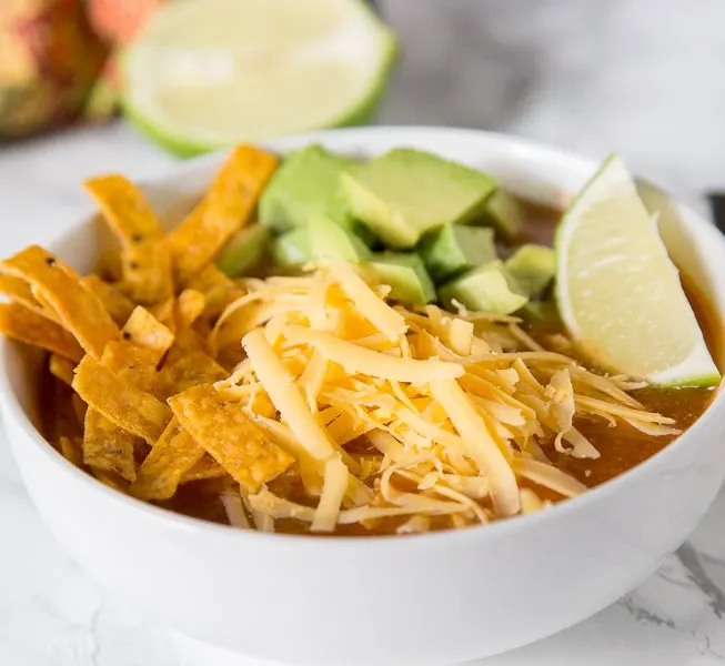 A close up tortilla soup topped with cheese