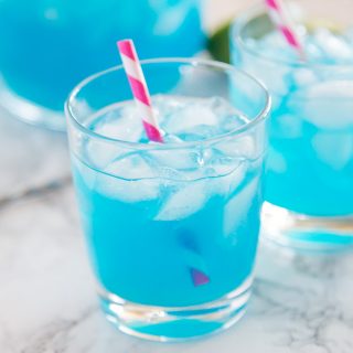 A cup of blue margarita with a straw
