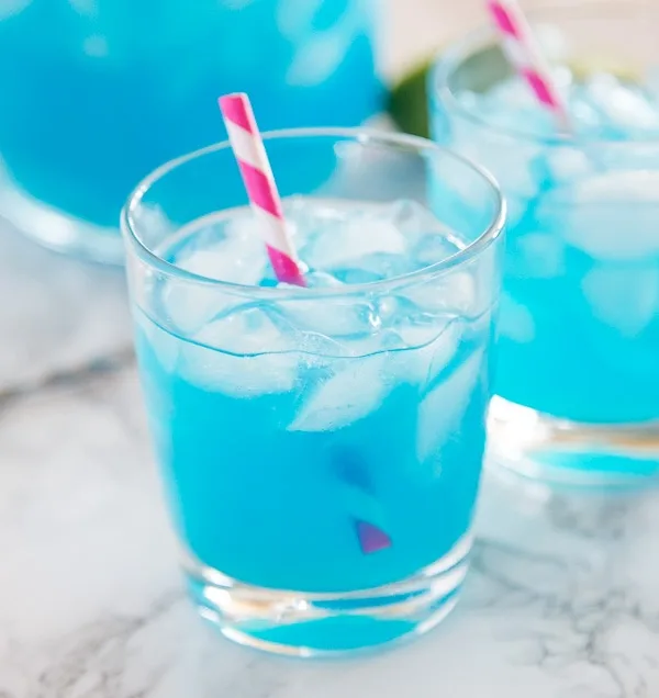 A cup of blue margarita with a straw