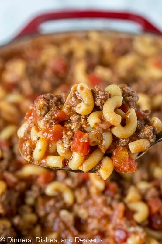 Close up of a spoonful of goulash with a pot of goulash in the background