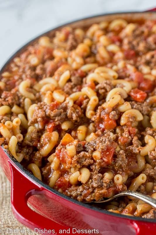 A dutch oven filled with goulash, with a spoon in it