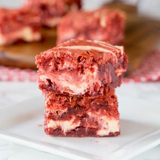 red velvet brownies with cream cheese swirl stacked on a plate