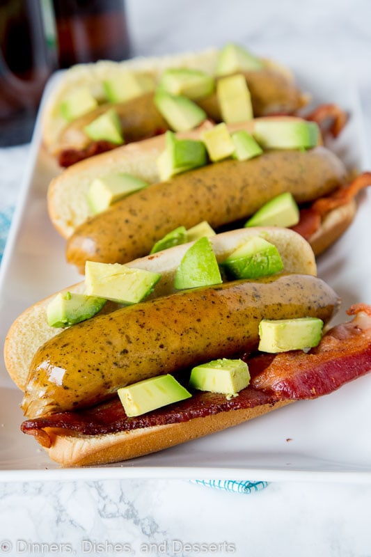 brats with avocado and bacon sitting on a plate