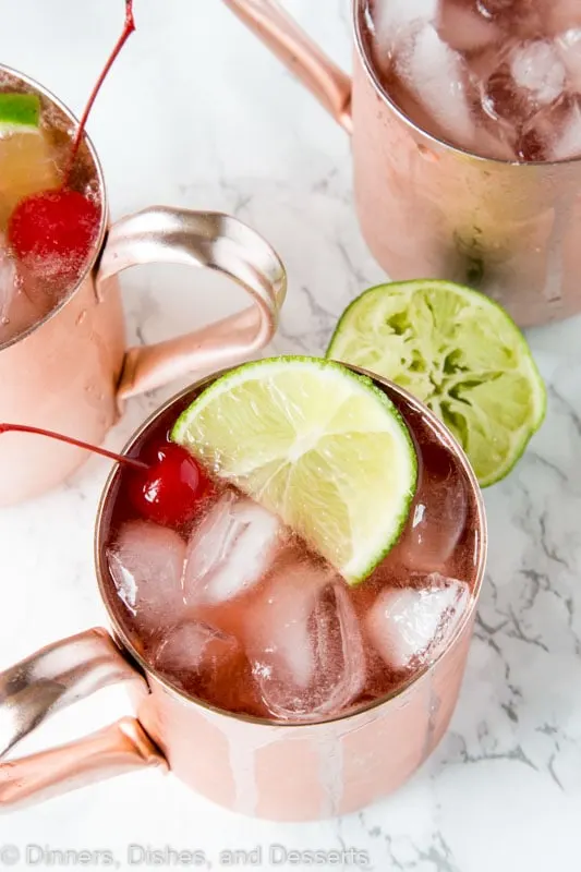 A close up of Cherry Lime and Moscow mule in a glass with lime slices