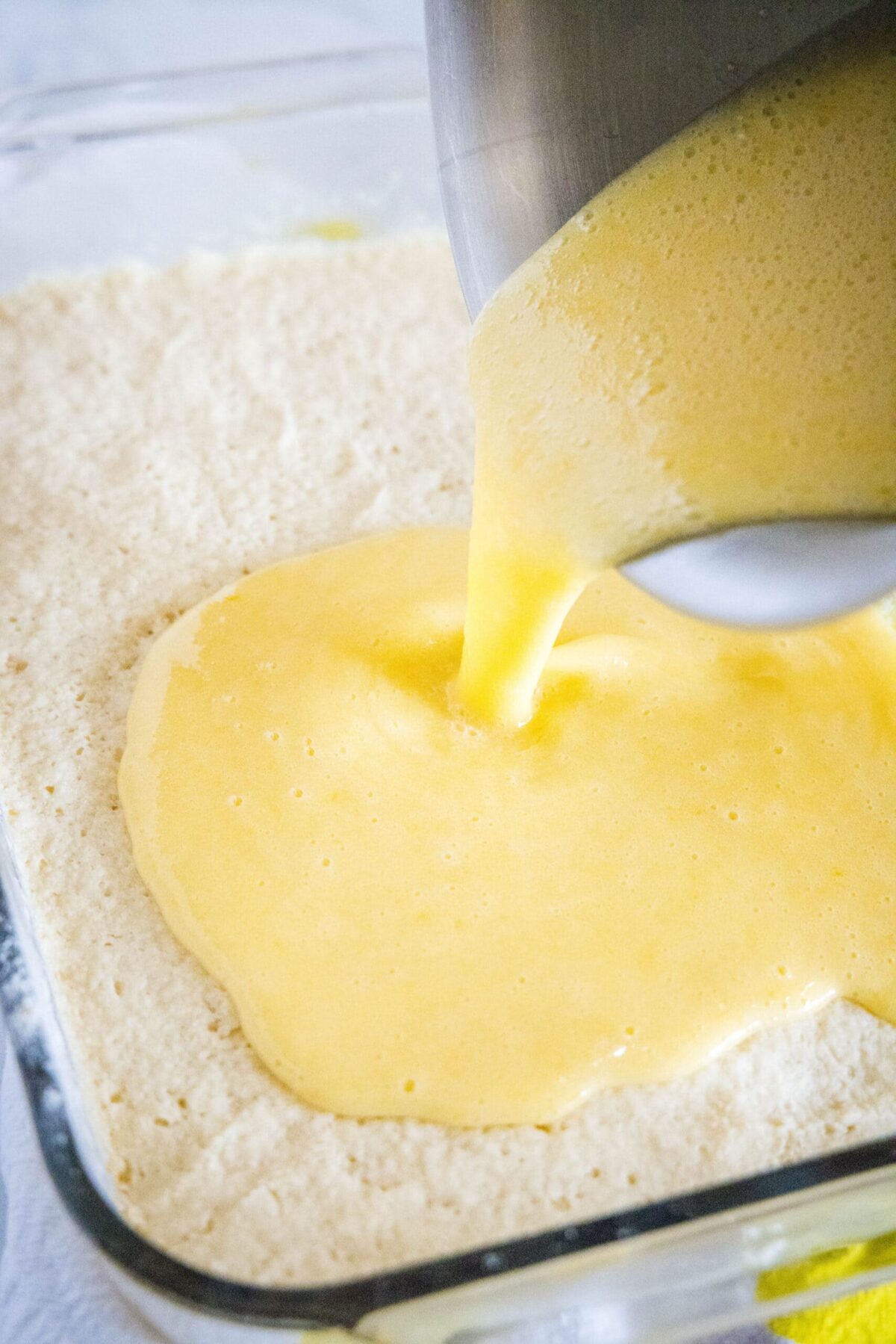 Lemon filling being poured on top of shortbread crust