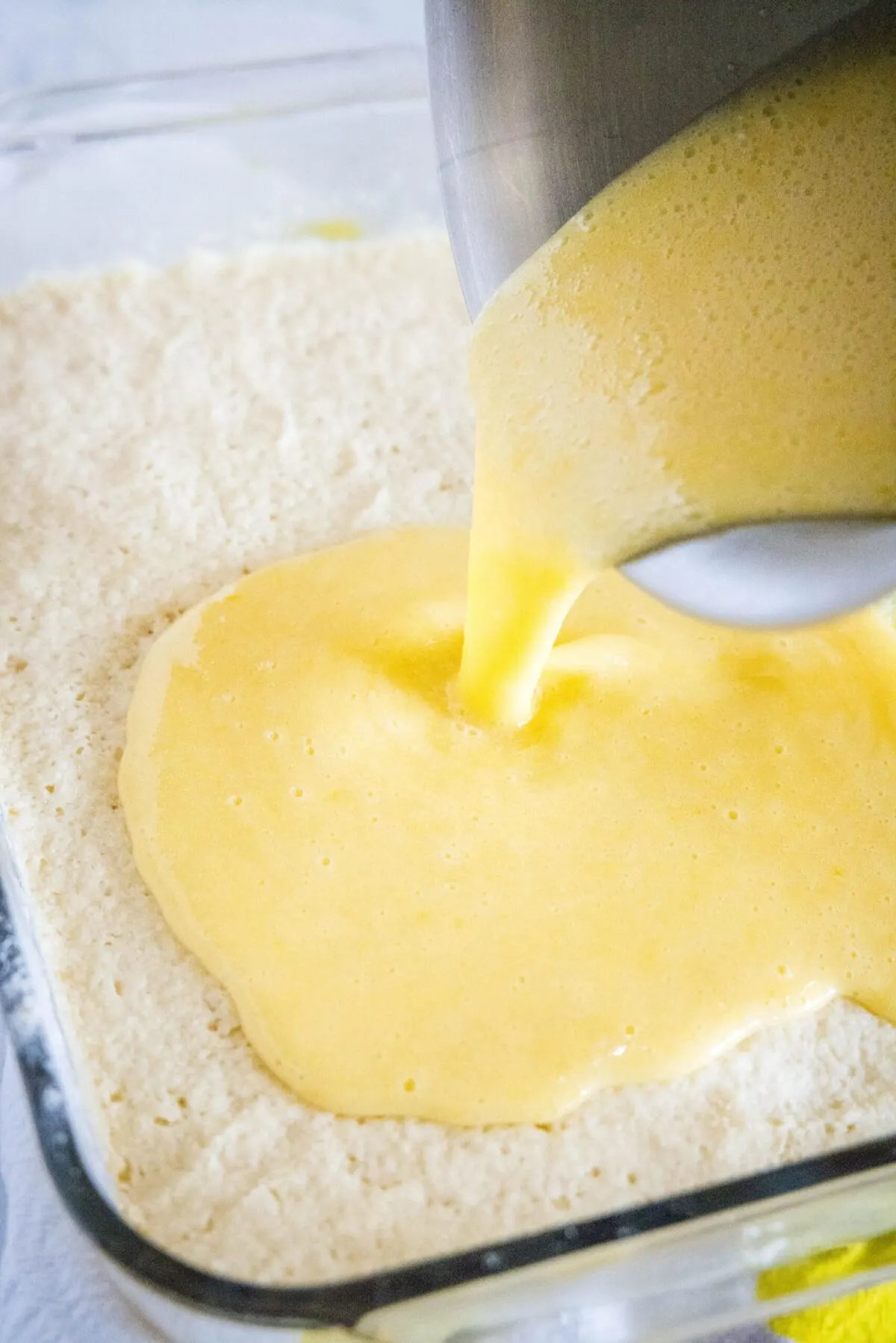 Lemon filling being poured on top of shortbread crust