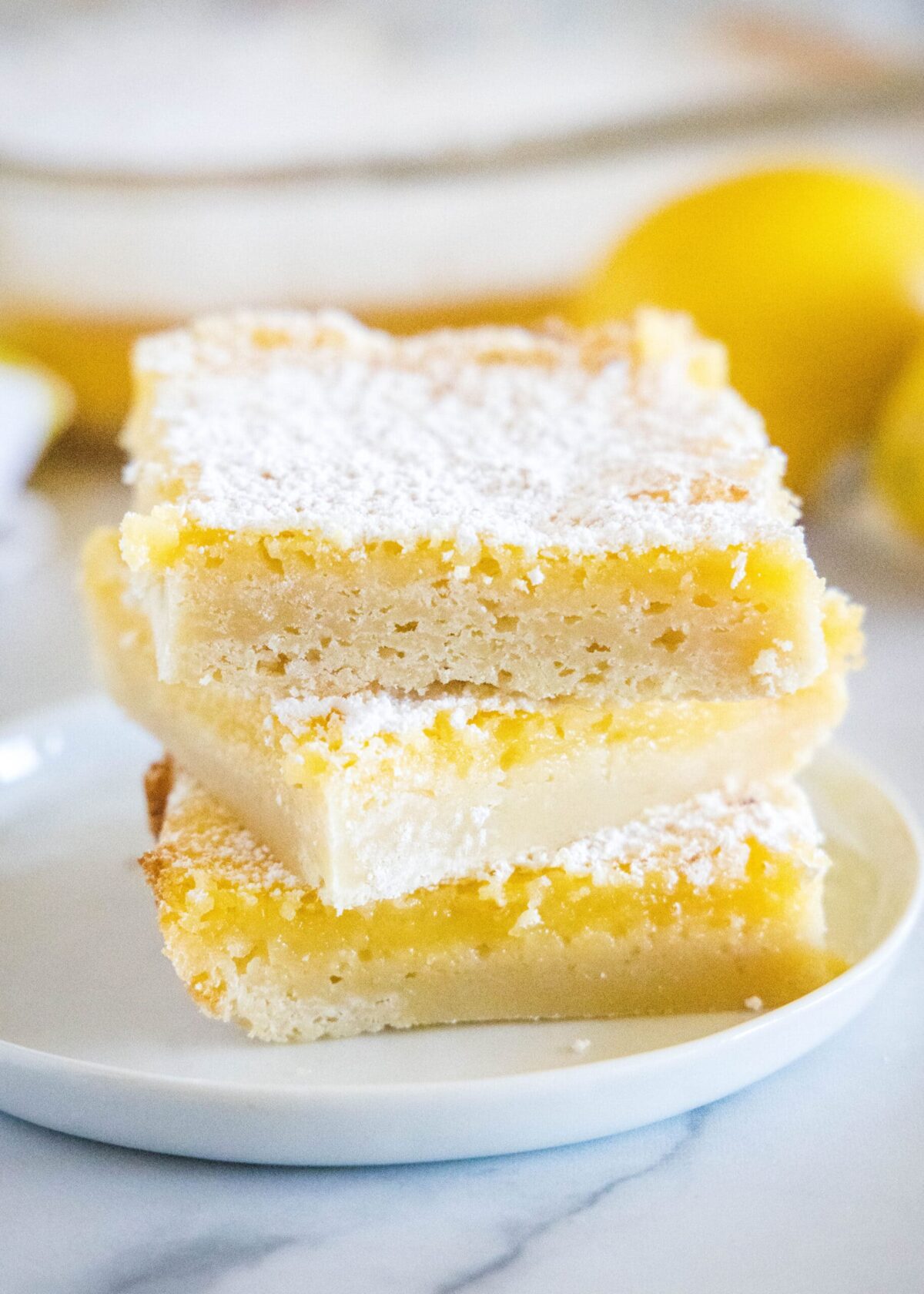 Close up of three lemon bars stacked on a plate