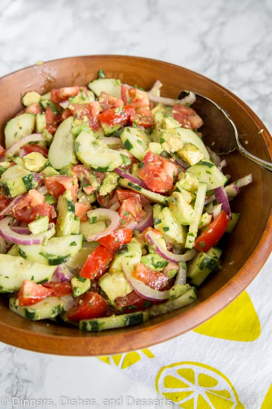 A bowl of food on a plate, with Salad and Cucumber, tomato, avoacdo