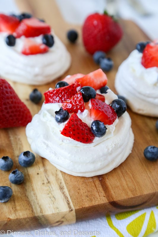 A piece of pavlova on a cutting board with berries