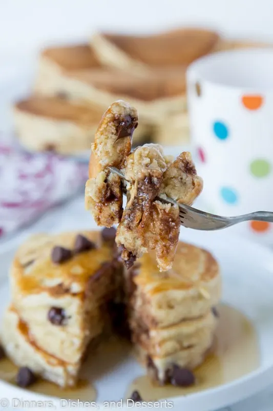 banana pancakes with chocolate chips stacked on a plate with a bite on the fork