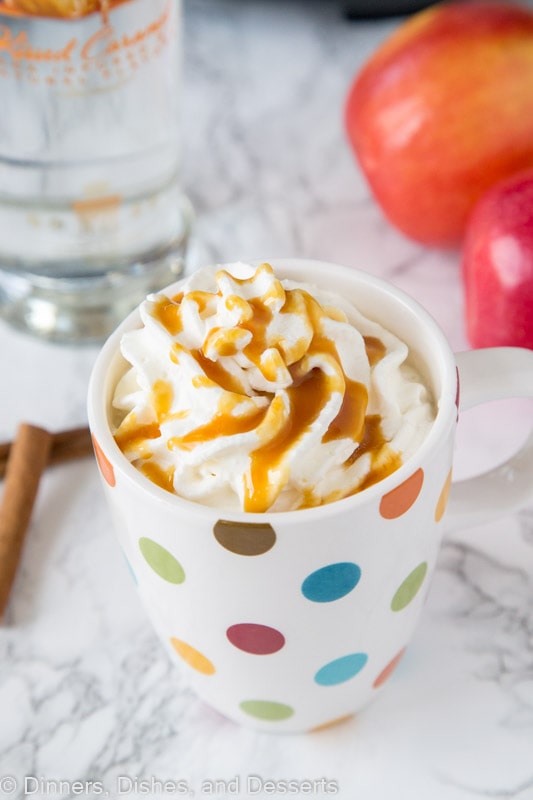 A close up of hot cider spiked with vodka topped with whipped cream
