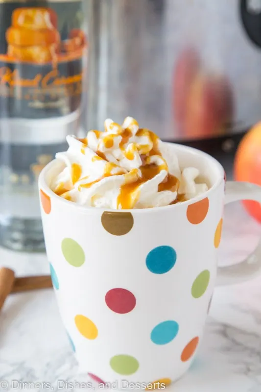 A close up of hot cider spiked with vodka topped with whipped cream