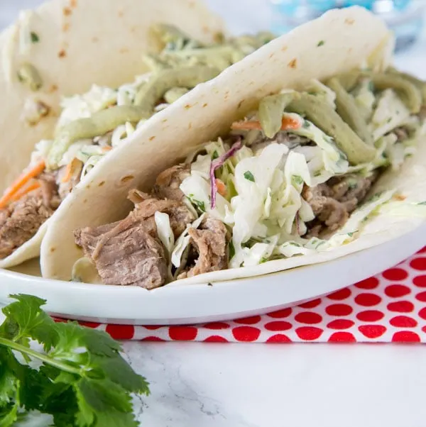 Instant Pot Pork Tacos - these pulled pork tacos are super tender and so delicious. Topped with a creamy Mexican slaw and avocado sauce!
