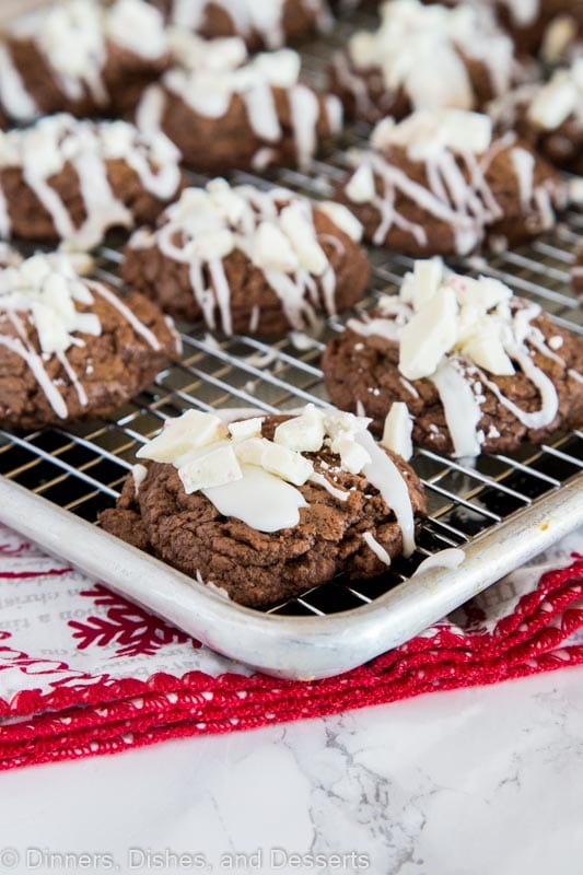 chocolate cookies with white chocolate drizzle on a cooling rack.