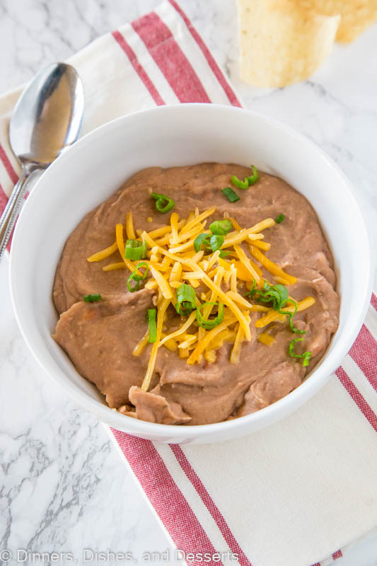 A bowl of refried beans topped with cheddar cheese