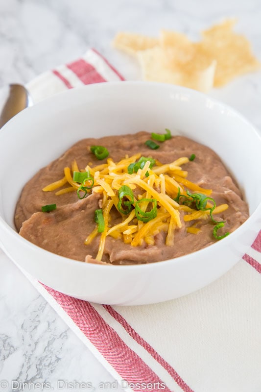 A bowl of refried beans topped with cheddar cheese