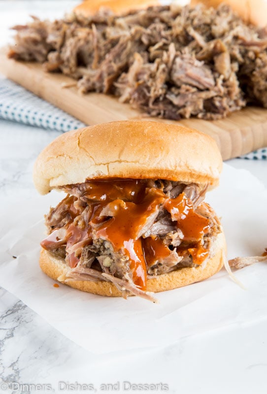 A sandwich sitting on top of a paper plate, with Pork and Pulled pork