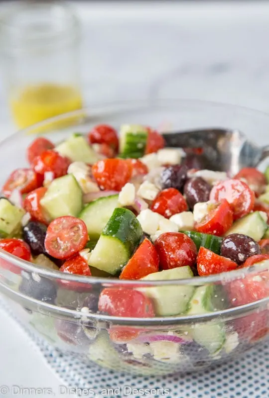 Easy summer salad with cucumbers, tomatoes, onions, olives and feta cheese topped with a lemony Greek dressing