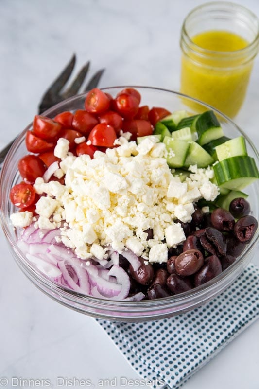 Greek salad recipe with dressing in bowl ready to be mixed together