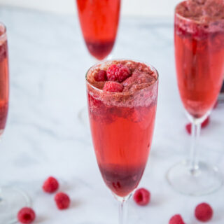 Raspberry Mimosas - A great drink for brunch or your next party.  Raspberry sorbet, champagne, raspberry liqueur and a few fresh raspberries make for a delicious cocktail.
