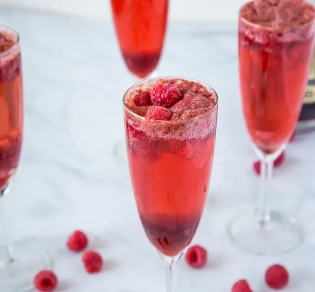 Raspberry Mimosas - A great drink for brunch or your next party.  Raspberry sorbet, champagne, raspberry liqueur and a few fresh raspberries make for a delicious cocktail.