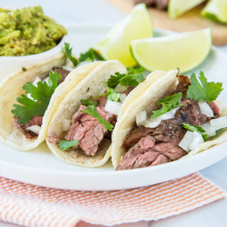 Flank Steak Tacos - Juicy flank steak marinated in lime juice, garlic, cilantro and more. Served in tortillas with your favorite toppings for taco night! 