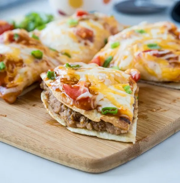 A slice of mexican pizza sitting on top of a wooden cutting board