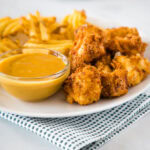 chick fil a chicken nuggets on a plate with fries and dipping sauce