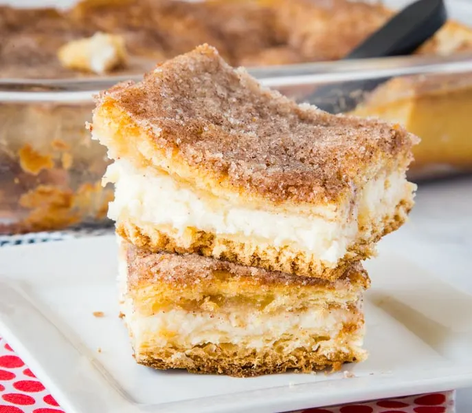 Sopapilla Cheesecake Bars - flaky pastry around a thick and creamy layer of cheesecake.  Then topped with butter and cinnamon sugar. A quick and easy version of sopapillas you can make in no time! 