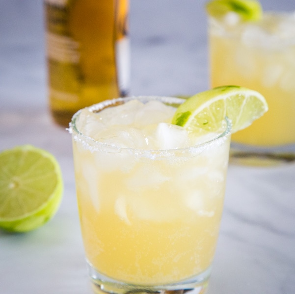 A glass of margarita with bottle of beer in the background with Margarita