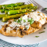 A plate o chicken and asparagus on a table
