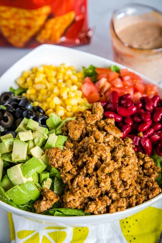 Taco salad with beans, tomatoes, corn, avocado, black olives, taco meat, and cheese Doritos