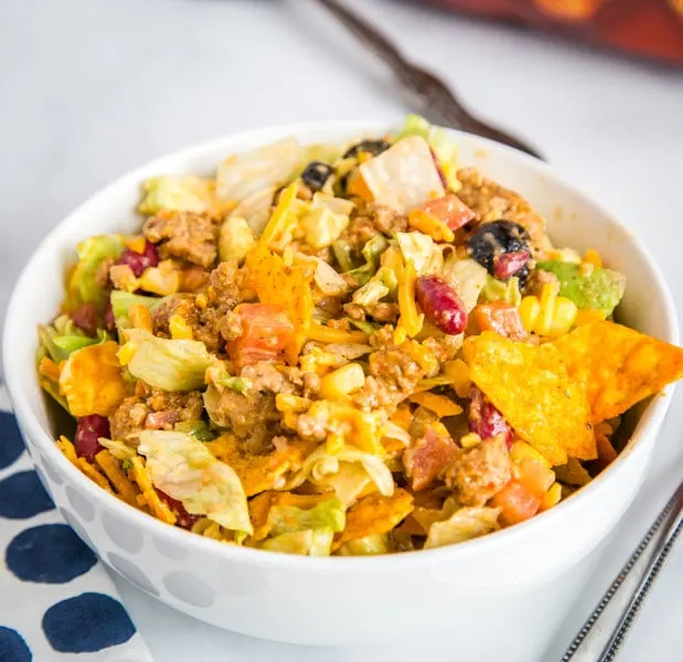 A bowl of food on a plate, with Salad and Taco