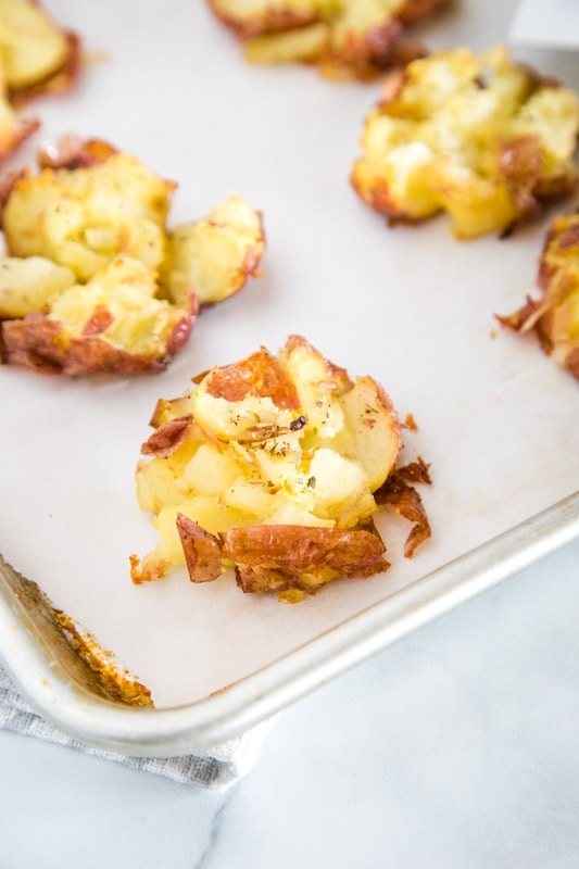 Crispy Smashed Potatoes Recipe  - These smashed potatoes are baked until they are crispy and delicious!  Topped with a plenty of garlic to make them the perfect side dish for any night of the week.  