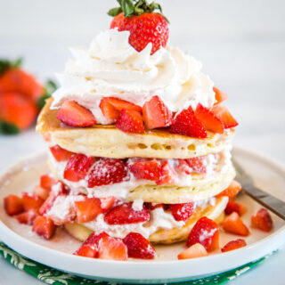 Pancakes layered with whipped cream and strawberries
