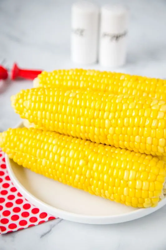 fresh corn on the cob cooked in the instant pot sitting on a white plate