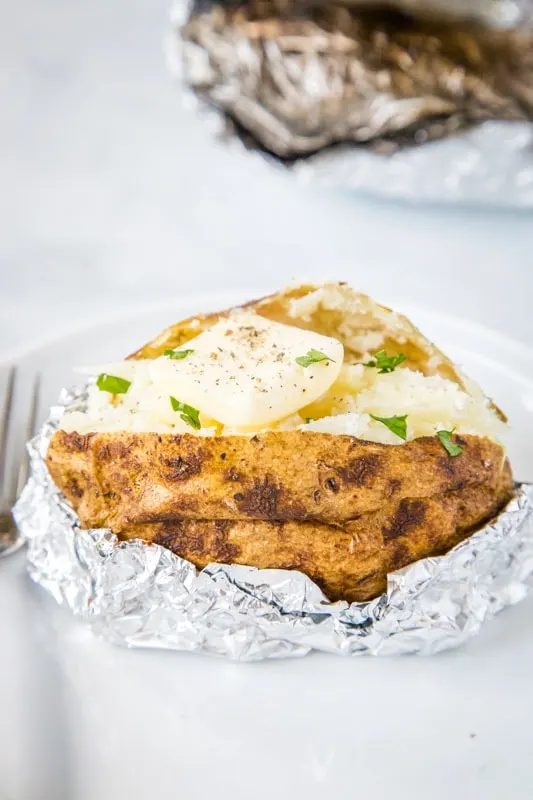 baked potatoes on the grill with butter and chives