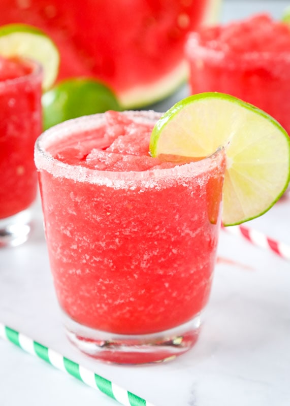 frozen watermelon margaritas in glasses with lime wedges