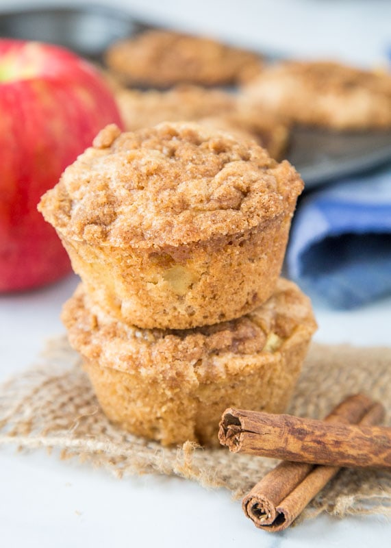 apple muffins stacked next to cinnamon sticks