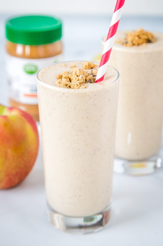 Apple smoothie with granola in a glass with a straw