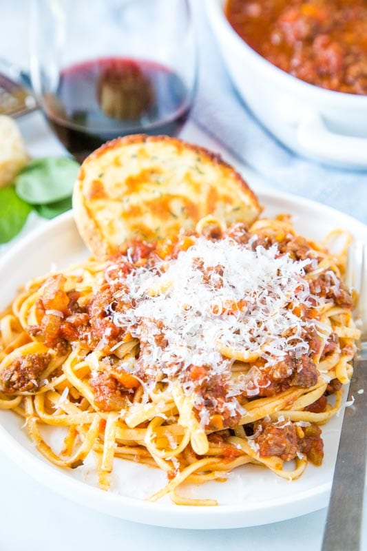 Plate of pasta with meat sauce topped with parmesan cheese
